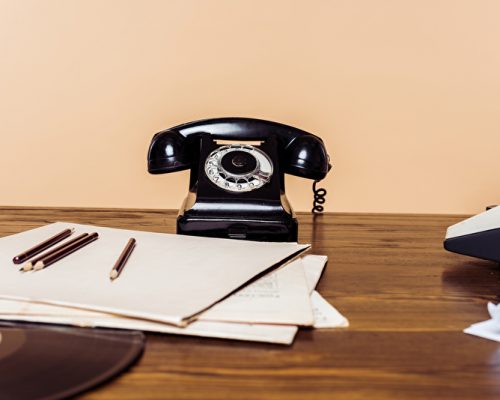 Closeup Aufnahme von Telefon mit Wählscheibe auf Holztisch mit Schreibmaschine und Vinyl-Scheibe auf Tisch